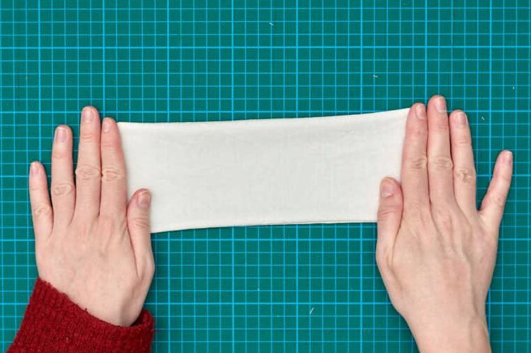 two hands holding eye pillow liner flat on green cutting mat