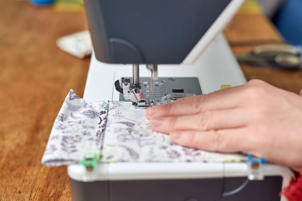 close up of sewing machine, sewing fabric with flowers