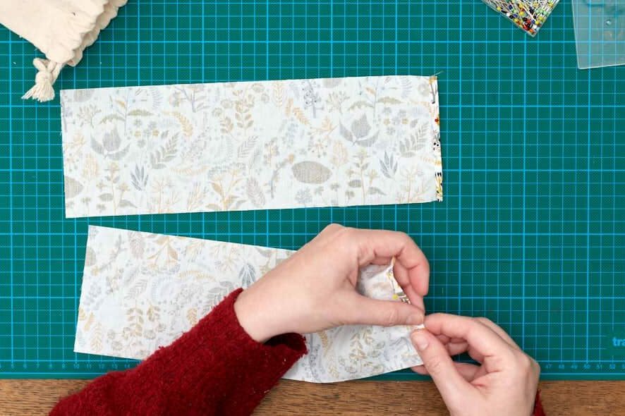 Hands pinning a small hem in fabric