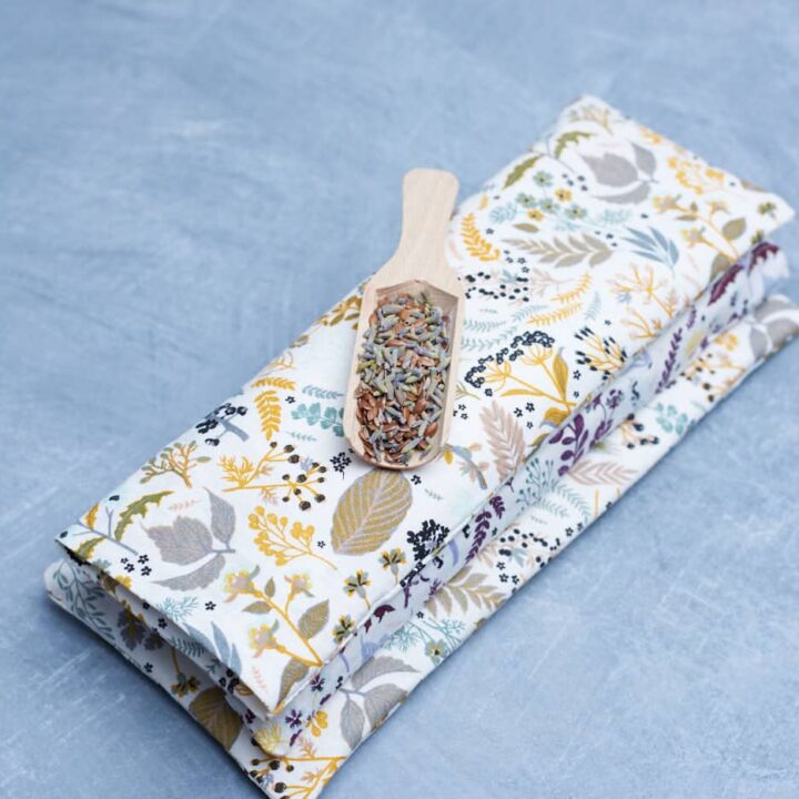 stack of three eye pillows. A little wooden spoon with mixture of flaxseed and dried lavender on top