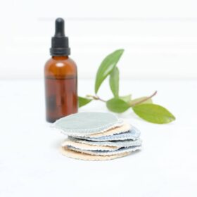 Stack of facial rounds with brown bottle and green leaves in the background