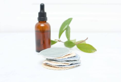Stack of facial rounds with brown bottle and green leaves in the background