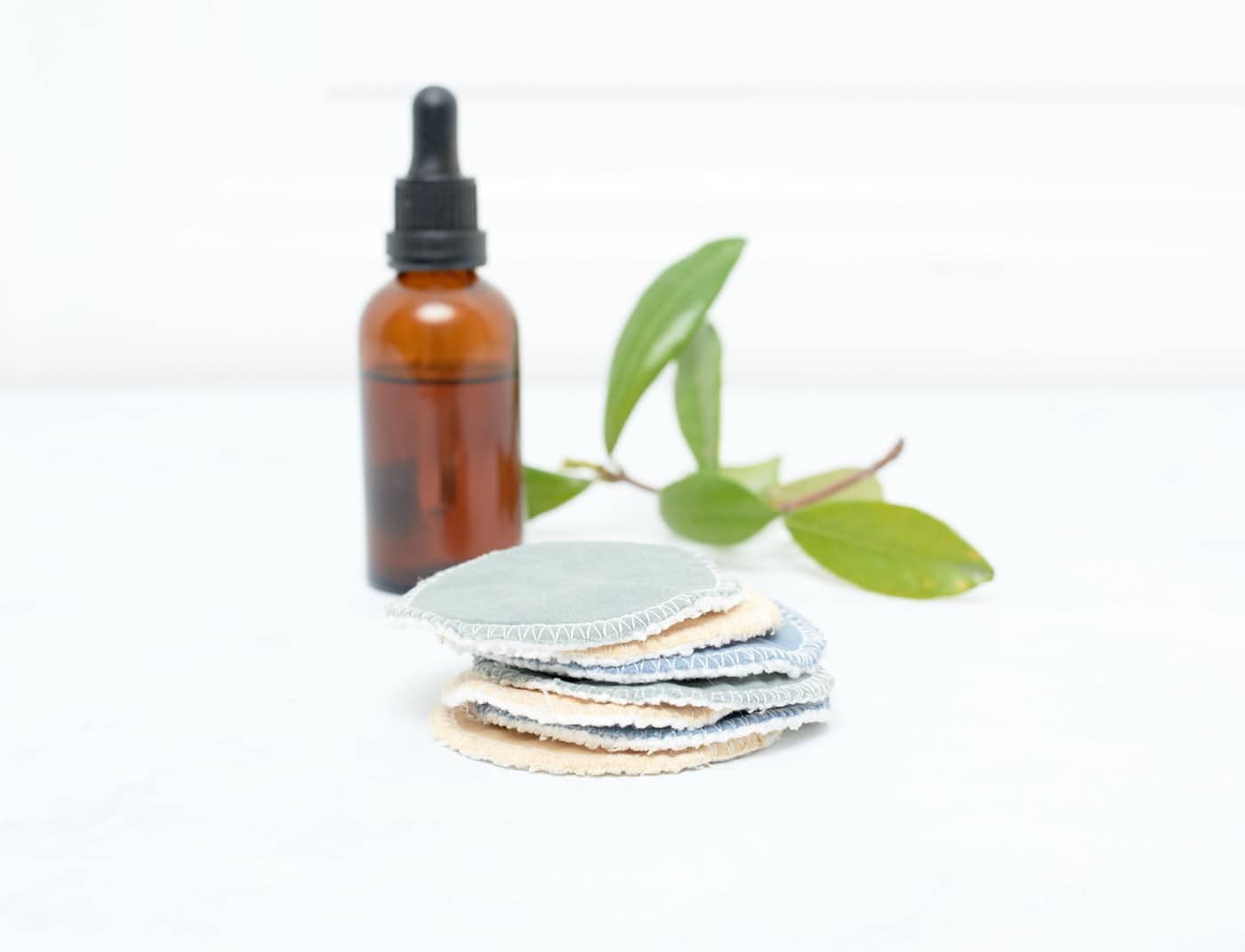Stack of facial rounds with brown bottle and green leaves in the background