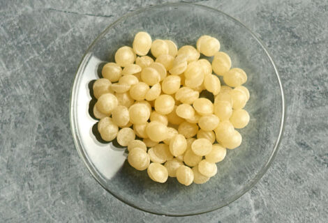 unrefined beeswax pellets on a small glas dish